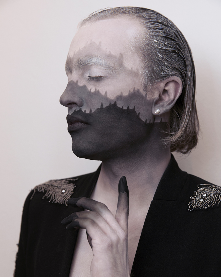 Jesse Clark posing with black and white facepaint that resembles a mountain range against a white background